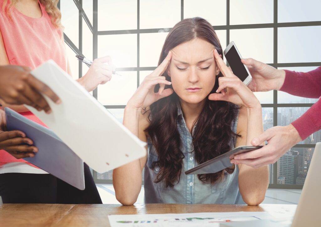 Overwhelmed woman surrounded by coworkers' demands — get help from a workplace bullying lawyer.