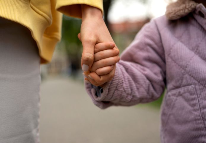 Adult holding child’s hand as part of guardianship application and legal care process