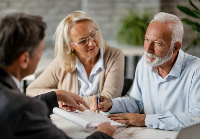 Senior couple meeting with lawyer to sign documents while writing a will