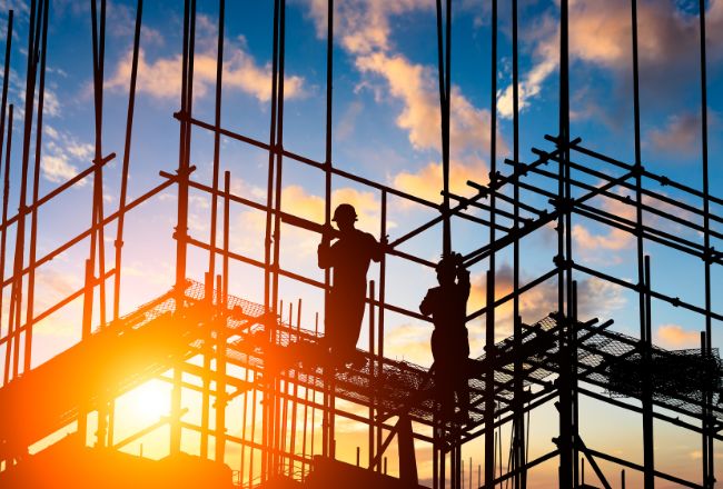 Construction workers on scaffolding at sunset symbolising property development projects managed by expert development lawyers.