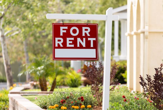 For rent sign in front of residential home representing property lease contract lawyers assisting with rental agreements.