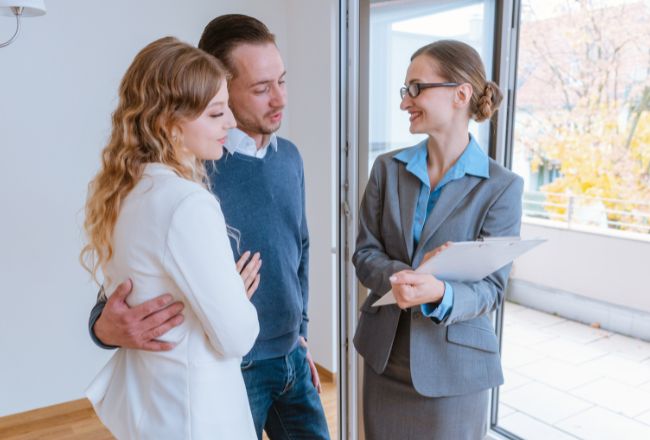 Couple discussing property details with real estate professional while purchasing a house in NSW.