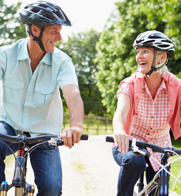Smiling senior couple cycling outdoors after setting up enduring guardianship plans.