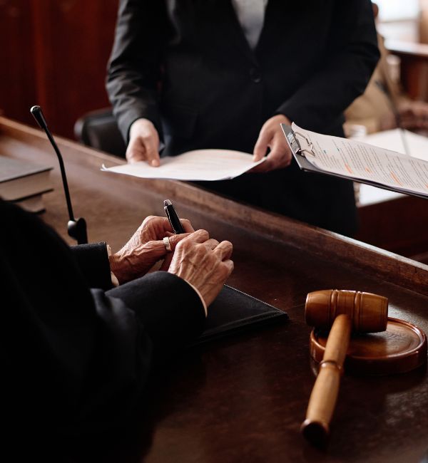 Litigation lawyer presenting legal documents to a judge during courtroom proceedings.