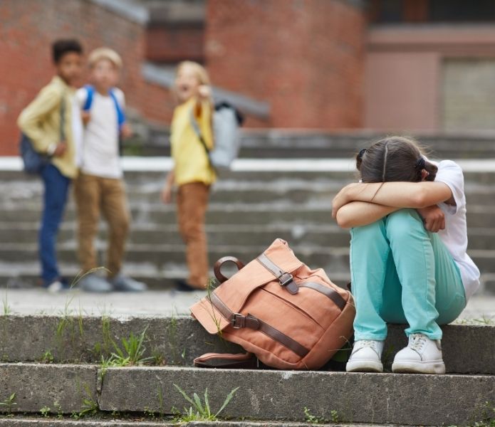 Sad child sitting on school steps after being bullied showing legal rights to sue school for bullying.